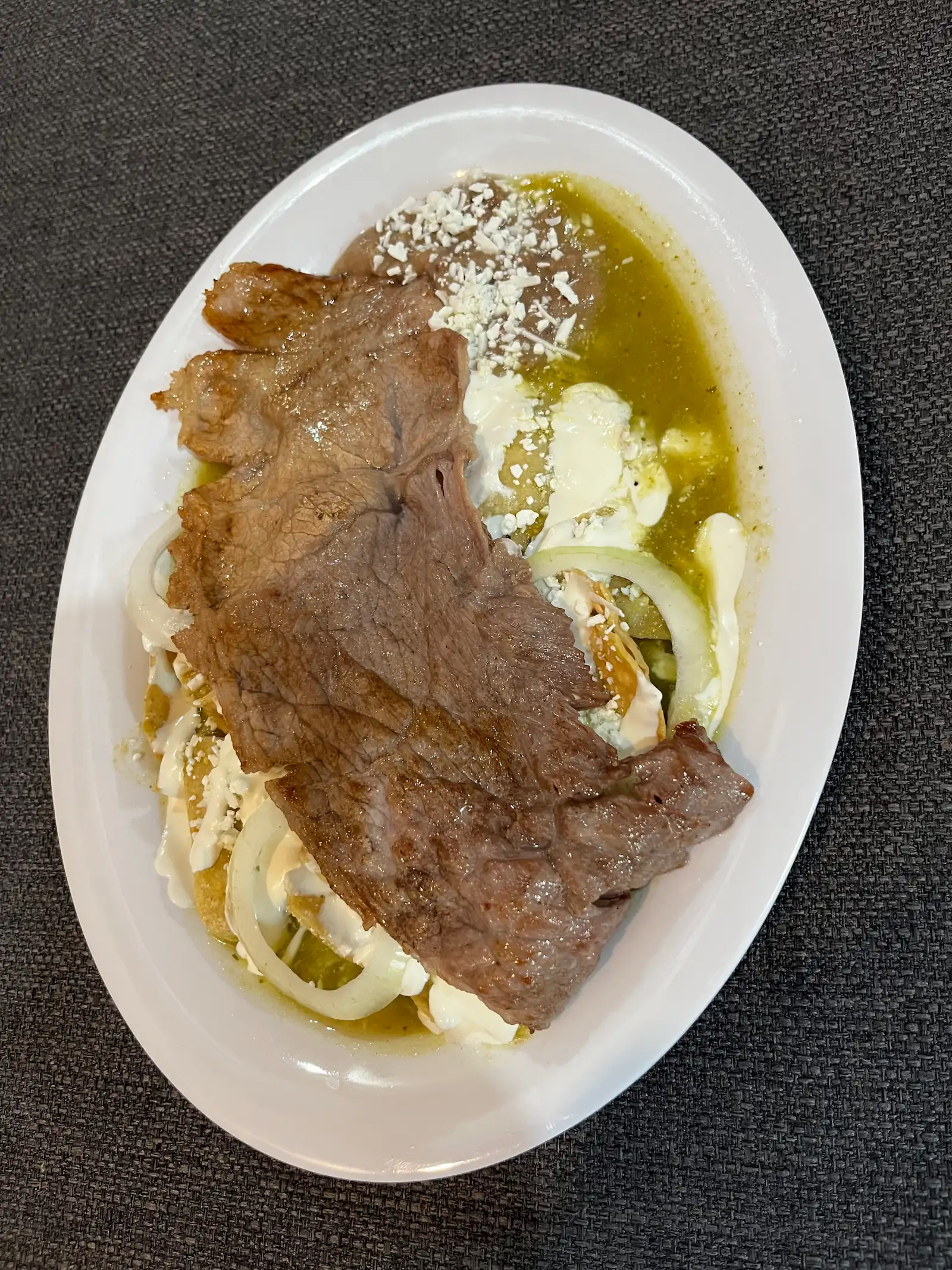 Chilaquiles caseros bañados en salsa, con queso y crema